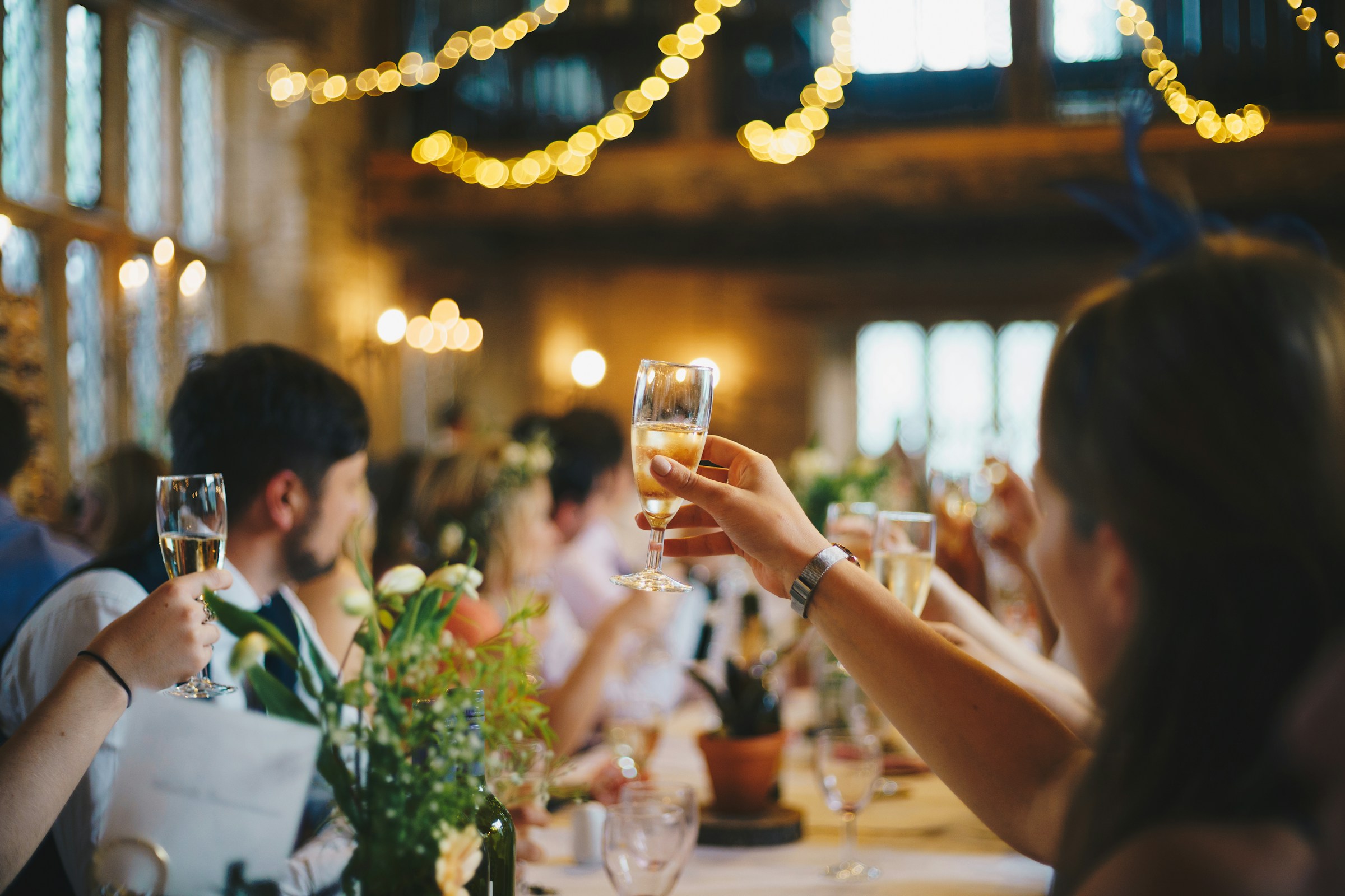Man and woman clink drinks together during cheers at wedding reception