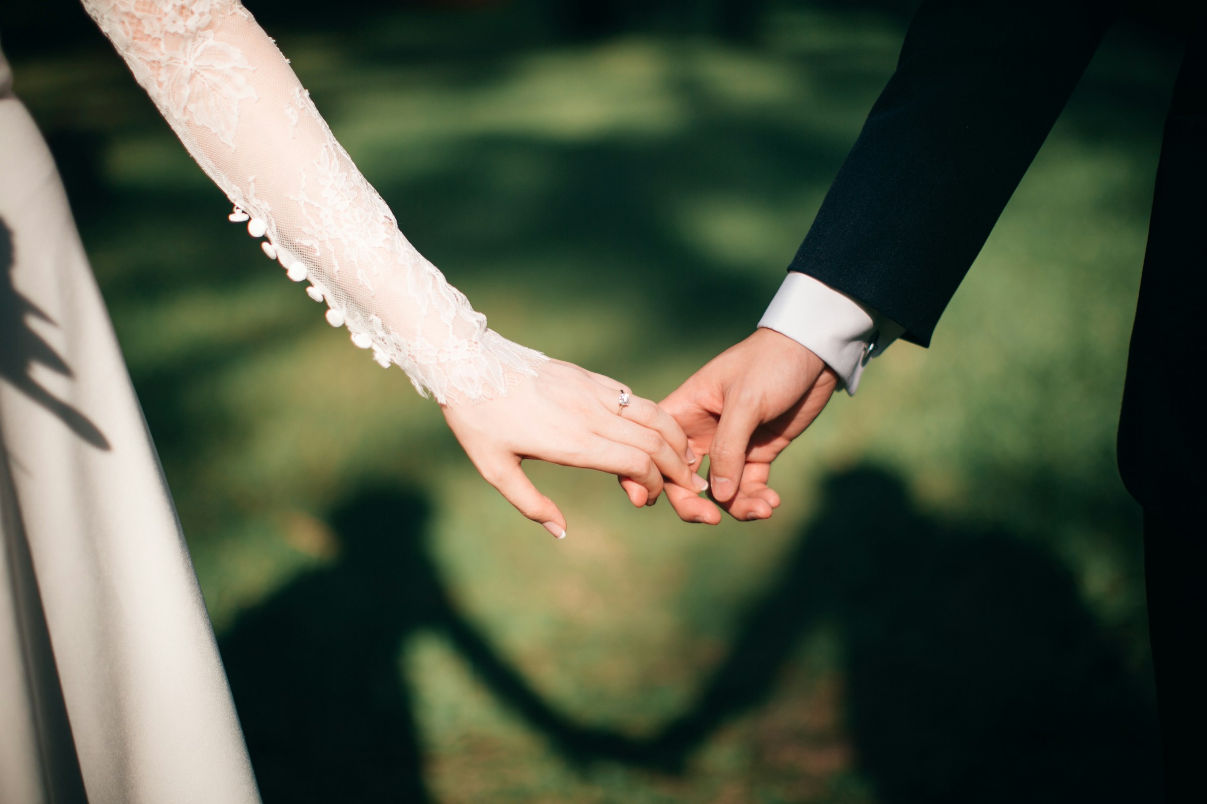 Bride and groom holding hands displaying wedding bands on their fingers
