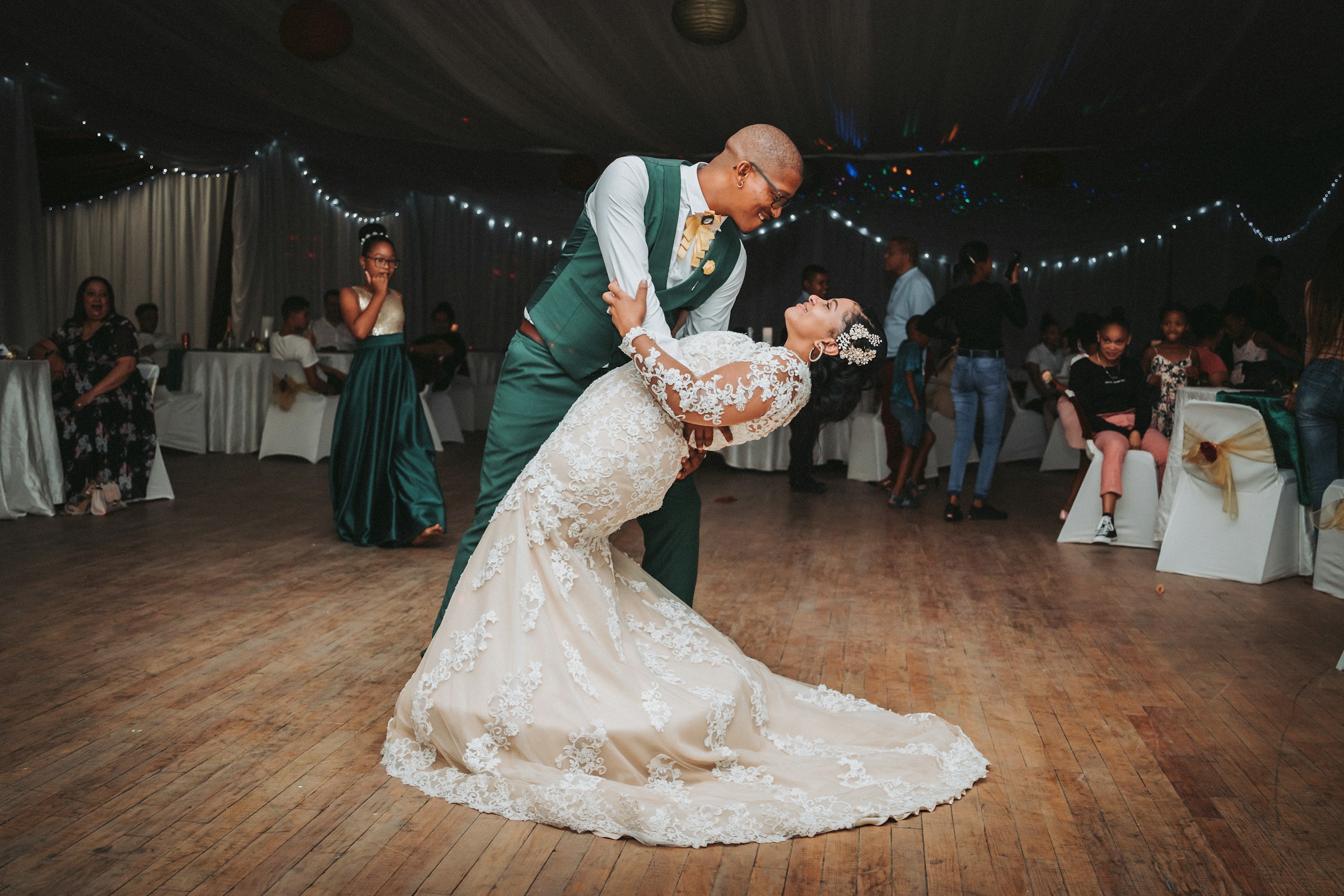 Groom leans bride back during first dance at wedding reception