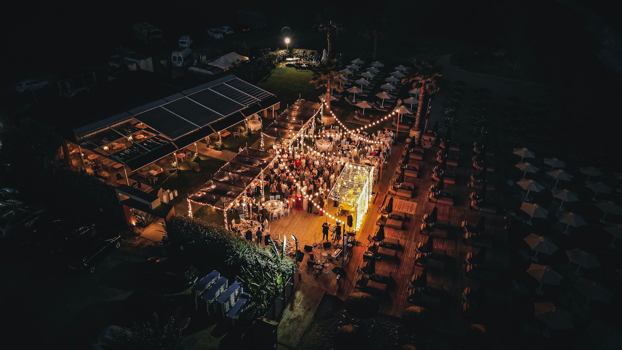 Drone videography of wedding reception lit up by string lights at night