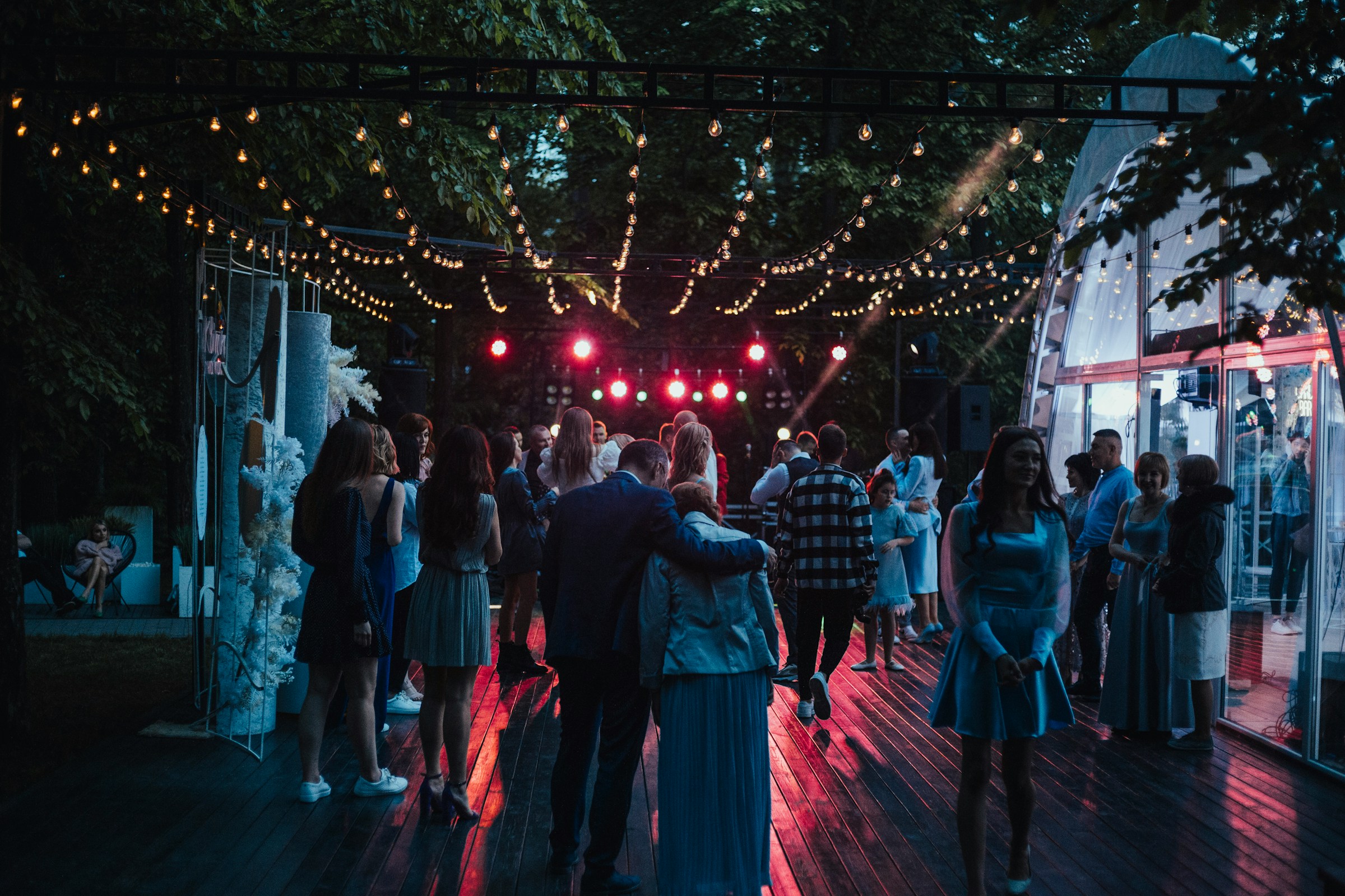 Many couples on dancefloor of wedding reception at night with lights shining on dancefloor